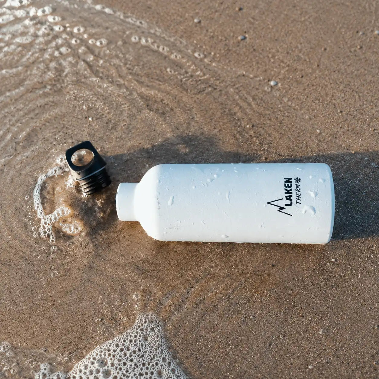 Botella LAKEN Futura abierta en una playa
